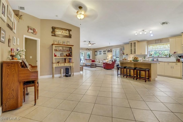 living room with light tile patterned flooring, ceiling fan, sink, and vaulted ceiling