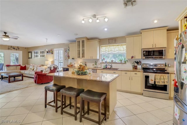 kitchen with sink, light tile patterned floors, a center island, and appliances with stainless steel finishes