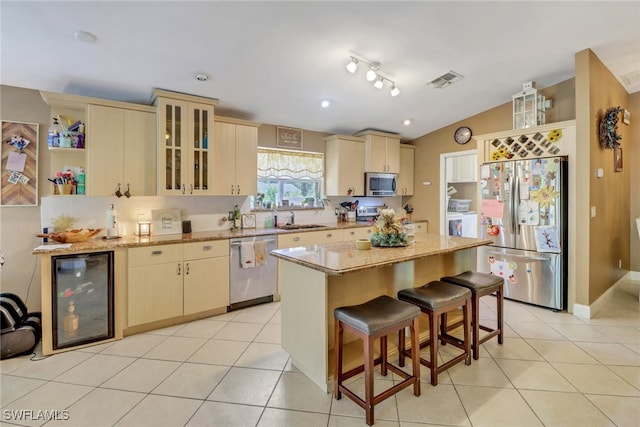 kitchen with appliances with stainless steel finishes, beverage cooler, a center island, and light tile patterned floors