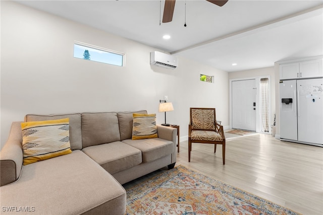 living room with a wall mounted air conditioner, ceiling fan, and light hardwood / wood-style flooring