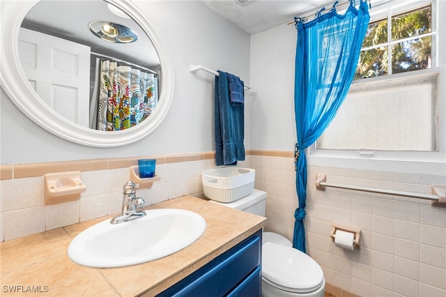 bathroom with vanity, tile walls, and toilet