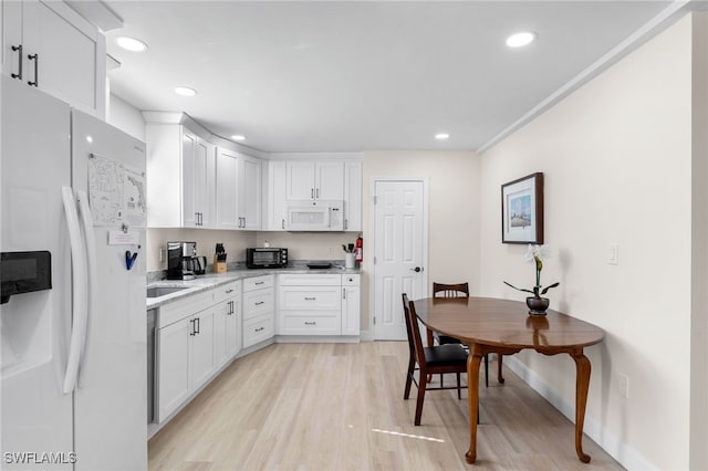 kitchen featuring white cabinets, light wood-type flooring, white appliances, and light stone countertops