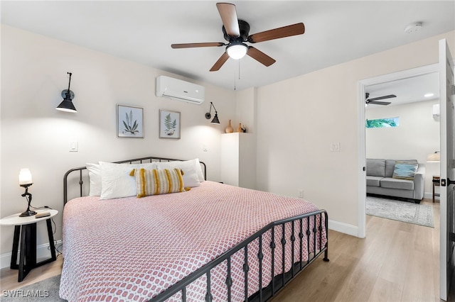 bedroom with light hardwood / wood-style floors, a wall mounted AC, and ceiling fan