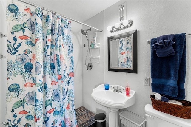 bathroom with curtained shower, toilet, and sink