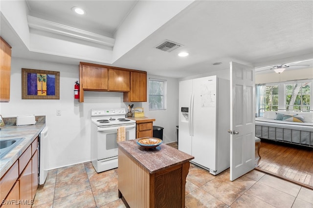 kitchen with ceiling fan, light hardwood / wood-style flooring, a center island, and white appliances