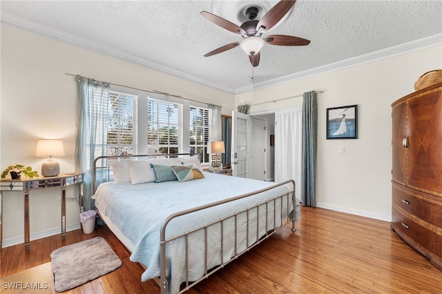 bedroom with ceiling fan, crown molding, a textured ceiling, and light hardwood / wood-style flooring