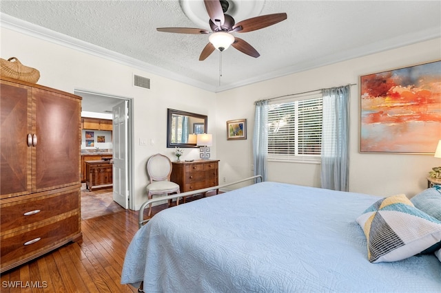 bedroom featuring ceiling fan, dark hardwood / wood-style flooring, ensuite bathroom, crown molding, and a textured ceiling