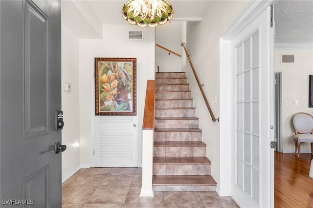 staircase featuring crown molding, wood-type flooring, and a textured ceiling