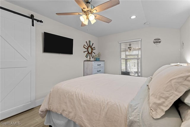 bedroom with ceiling fan, light hardwood / wood-style floors, and a barn door