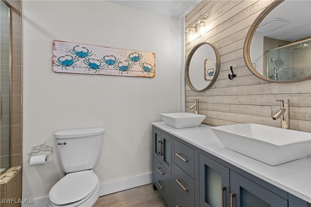 bathroom featuring toilet, vanity, wood-type flooring, wooden walls, and an enclosed shower