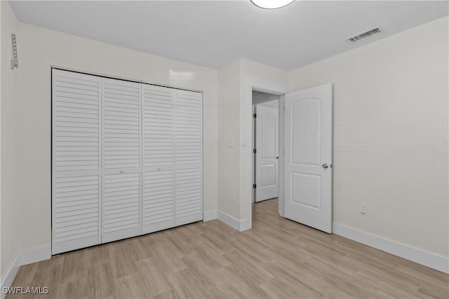 unfurnished bedroom with light wood-type flooring and a closet