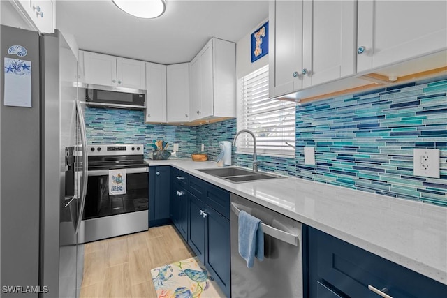 kitchen featuring stainless steel appliances, blue cabinets, white cabinets, and sink