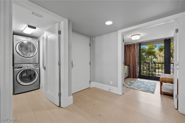 washroom with light hardwood / wood-style floors and stacked washer and clothes dryer