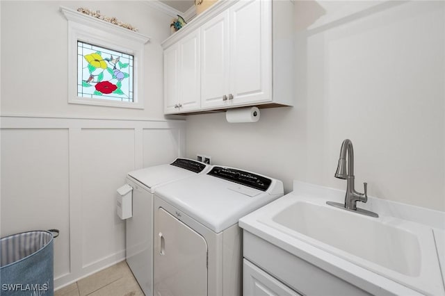 laundry area featuring a wainscoted wall, cabinet space, a decorative wall, a sink, and independent washer and dryer