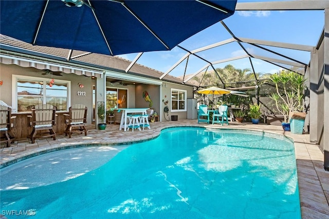 pool featuring glass enclosure, ceiling fan, and a patio area