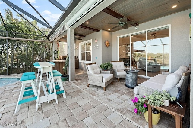 view of patio featuring glass enclosure, outdoor lounge area, an outdoor bar, and a ceiling fan