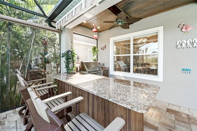 view of patio / terrace featuring a bar, an outdoor kitchen, ceiling fan, and grilling area