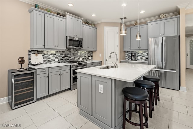 kitchen featuring gray cabinetry, beverage cooler, stainless steel appliances, a sink, and light countertops