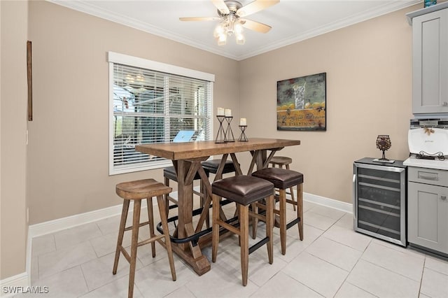 dining room with beverage cooler, ornamental molding, ceiling fan, and baseboards