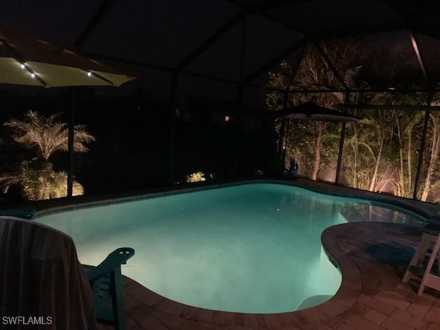 17773 Vaca Ct, Fort Myers, FL 33908 - pool at night featuring an outdoor pool, glass enclosure, and a patio