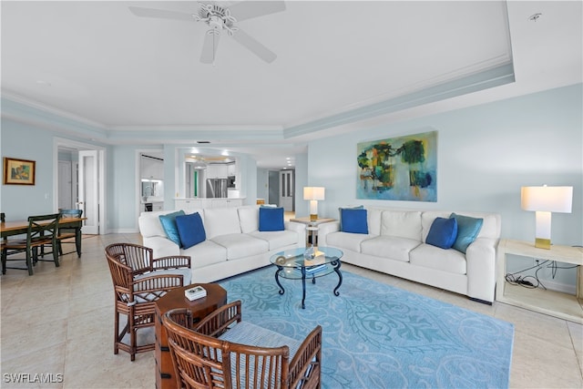 tiled living room with a raised ceiling, ceiling fan, and ornamental molding