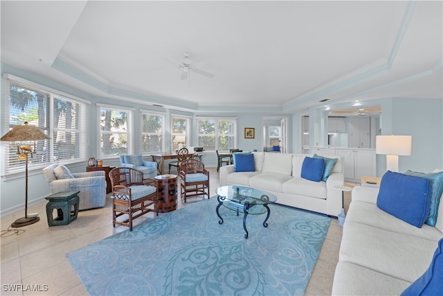 tiled living room featuring a tray ceiling, ceiling fan, and crown molding