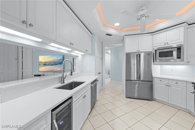 kitchen with sink, wine cooler, appliances with stainless steel finishes, a tray ceiling, and white cabinetry