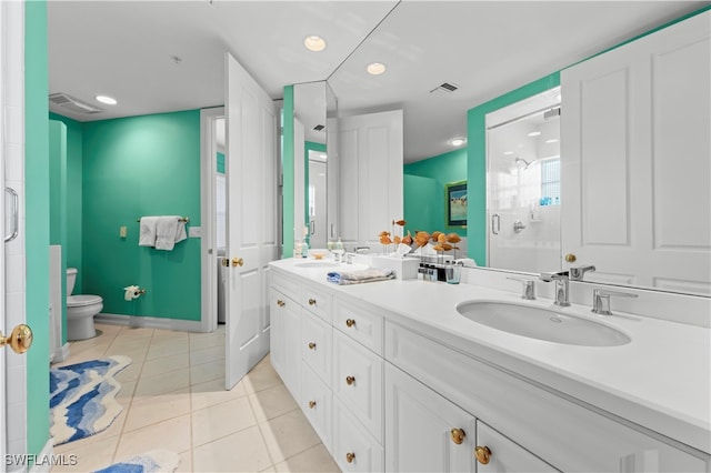 bathroom with toilet, vanity, tile patterned floors, and a shower with door