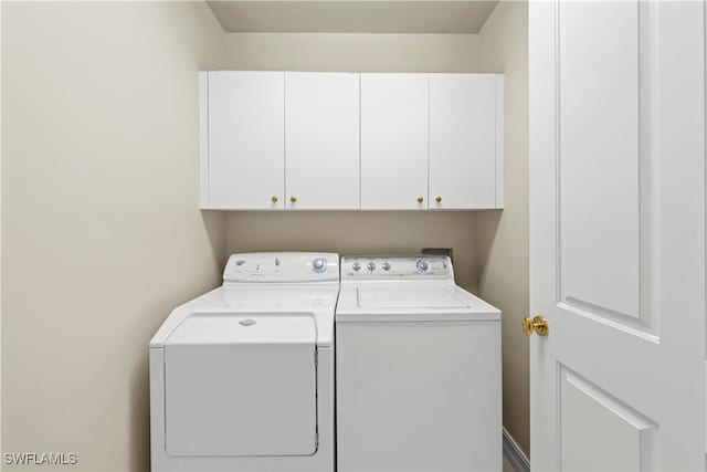 laundry area with separate washer and dryer and cabinets