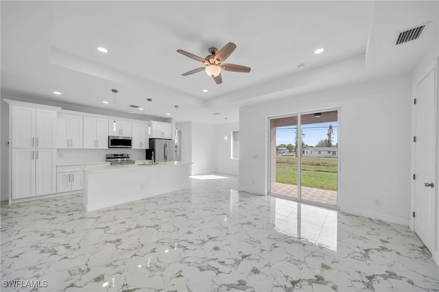 kitchen with white cabinetry, ceiling fan, decorative light fixtures, a kitchen island with sink, and appliances with stainless steel finishes