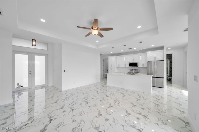 unfurnished living room with a raised ceiling, ceiling fan, french doors, and sink