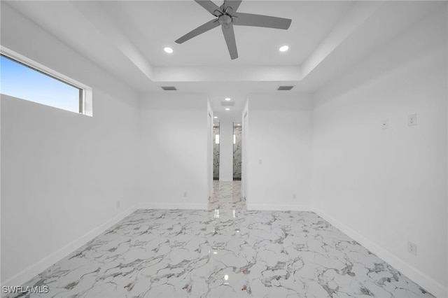 empty room featuring a raised ceiling and ceiling fan