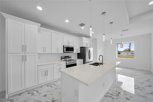 kitchen with pendant lighting, white cabinets, sink, an island with sink, and appliances with stainless steel finishes