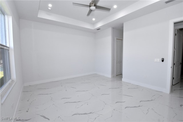 spare room featuring a raised ceiling and ceiling fan