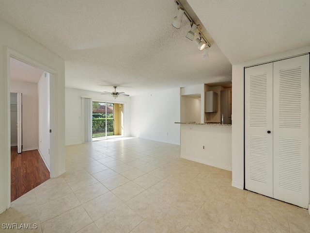 unfurnished living room featuring a textured ceiling, ceiling fan, light tile patterned floors, and track lighting