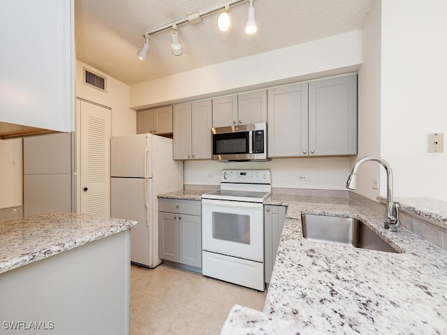 kitchen featuring gray cabinetry, white appliances, sink, rail lighting, and a textured ceiling