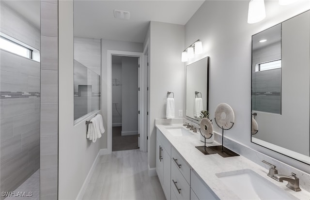 bathroom with a tile shower and vanity