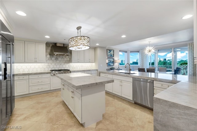 kitchen featuring sink, a center island, wall chimney exhaust hood, pendant lighting, and appliances with stainless steel finishes