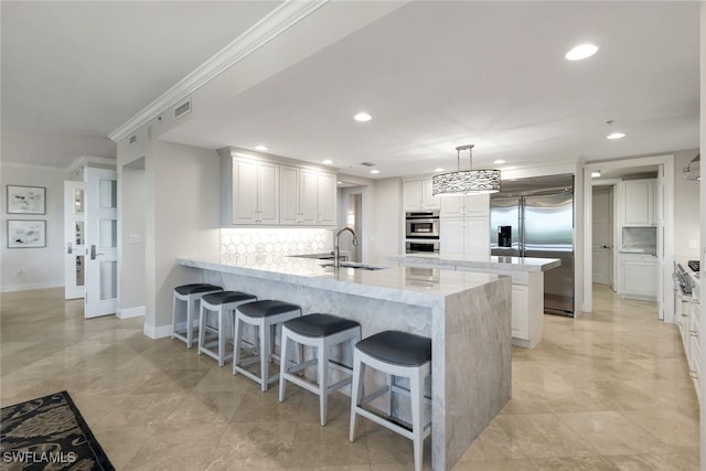 kitchen featuring appliances with stainless steel finishes, backsplash, sink, decorative light fixtures, and white cabinets