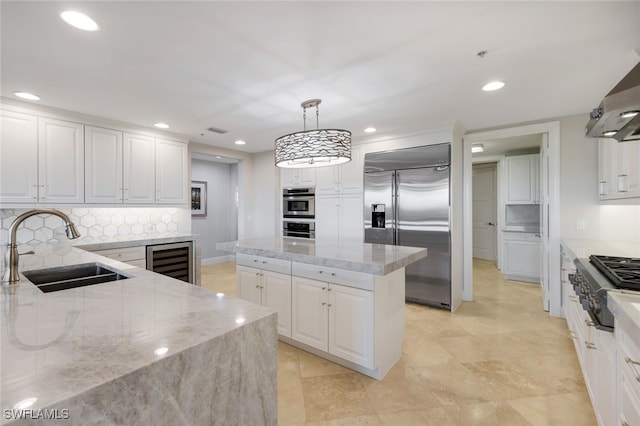 kitchen with sink, hanging light fixtures, appliances with stainless steel finishes, a kitchen island, and white cabinetry