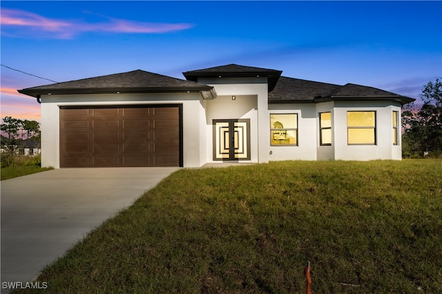 prairie-style home with a garage and a yard