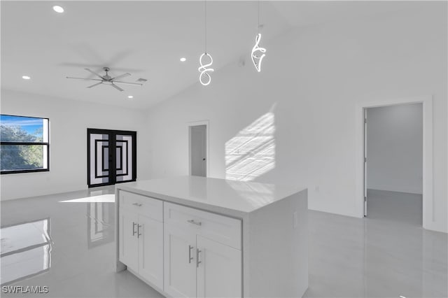 kitchen featuring ceiling fan, decorative light fixtures, a center island, white cabinetry, and lofted ceiling