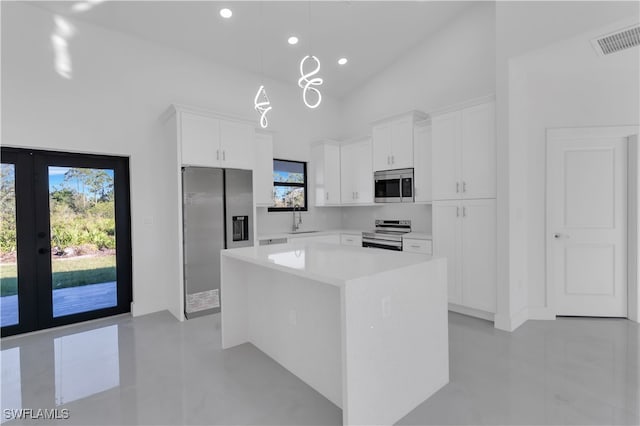 kitchen with pendant lighting, sink, a kitchen island, white cabinetry, and stainless steel appliances