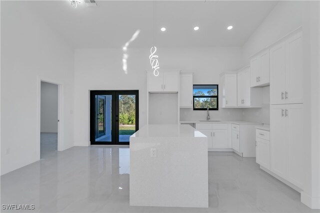 kitchen with white cabinets, a center island, a wealth of natural light, and sink