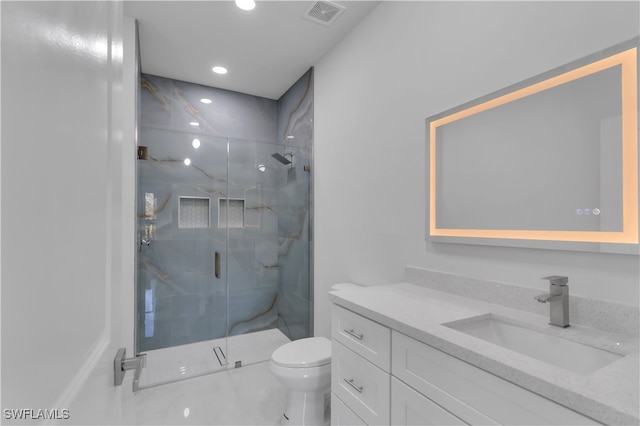 bathroom featuring vanity, toilet, and a shower with shower door