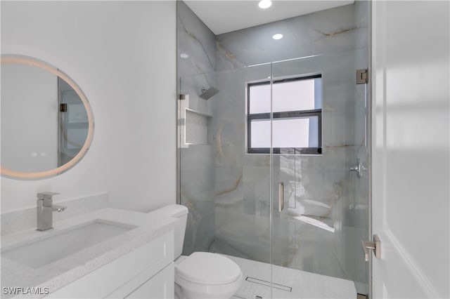 bathroom with a shower with door, vanity, and toilet