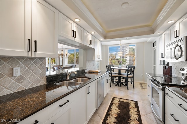 kitchen featuring sink, white cabinetry, dark stone countertops, a raised ceiling, and stainless steel appliances