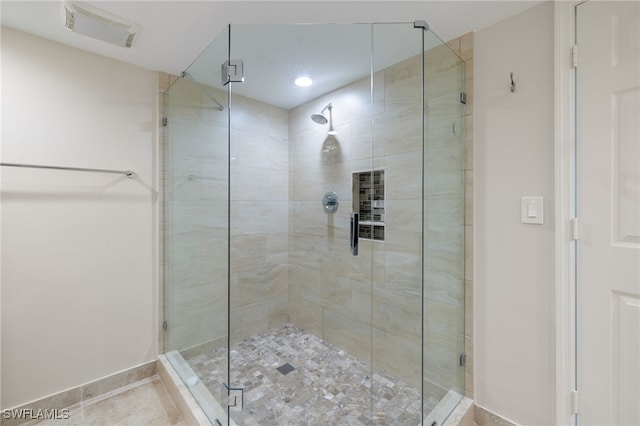 bathroom with a shower with door and tile patterned flooring