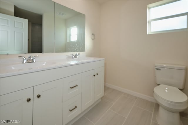 bathroom with tile patterned floors, plenty of natural light, toilet, and vanity