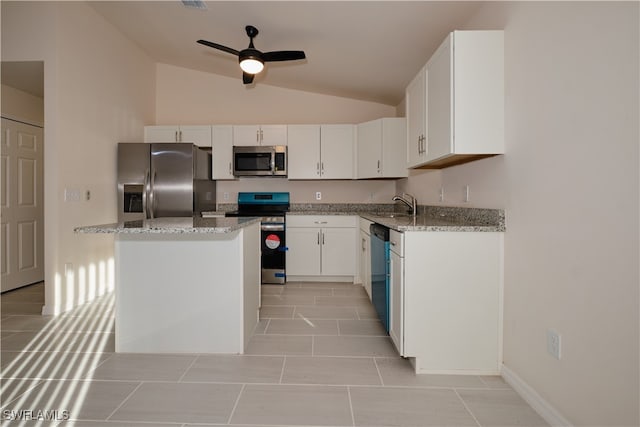 kitchen featuring light stone countertops, white cabinetry, appliances with stainless steel finishes, and vaulted ceiling